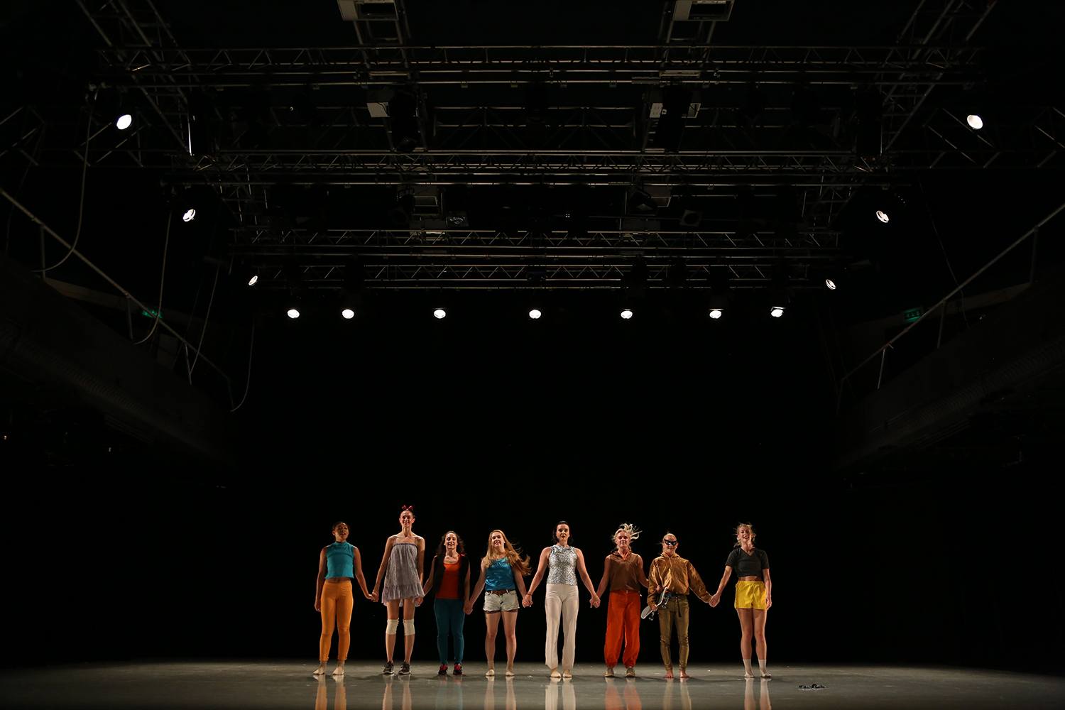 Dancers stand on stage holding hands ready to take a bow